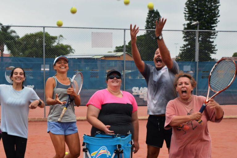 Some Mood Active participants celebrating on the court, smiling and throwing tennis balls in the air.