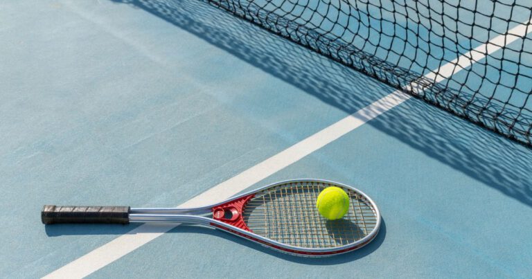 A single tennis ball on a racket lying on the court near the net.