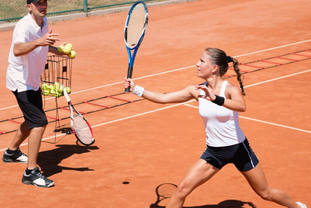 A tennis player about to hit a tennis ball that is in mid-air.